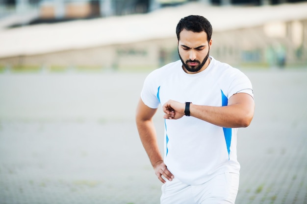 Sport man using headphones for listening music on morning run in park.