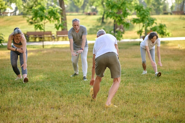 Sport in park Mature group of people exercising outdoors healthy lifestyle stretching body before workout