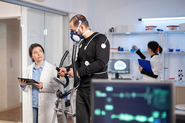 Sport scientist monitoring performance of athlete cardio, heart rate, testing cross training sportman in laboratory. Healthy body ekg laboratory run.