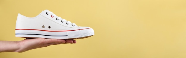 Sport sneakers on woman hand against yellow background