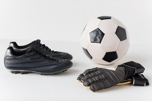 sport, soccer, football and sports equipment concept - close up of ball, boots and goalkeeper gloves