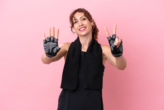 Sport sport woman with towel isolated on pink background counting seven with fingers