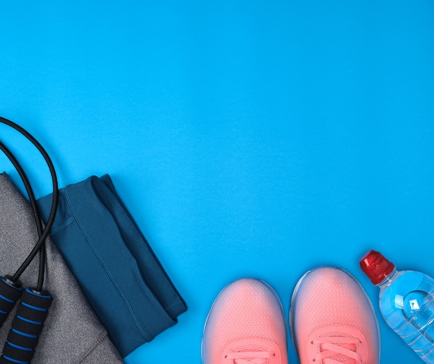 Sport textile shoes and other items for fitness on a blue background