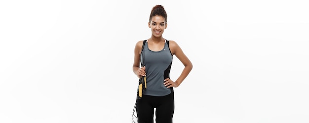 Sport training lifestyle and Fitness concept portrait of beautiful happy African American woman exercising with jumping rope Isolated on white studio background