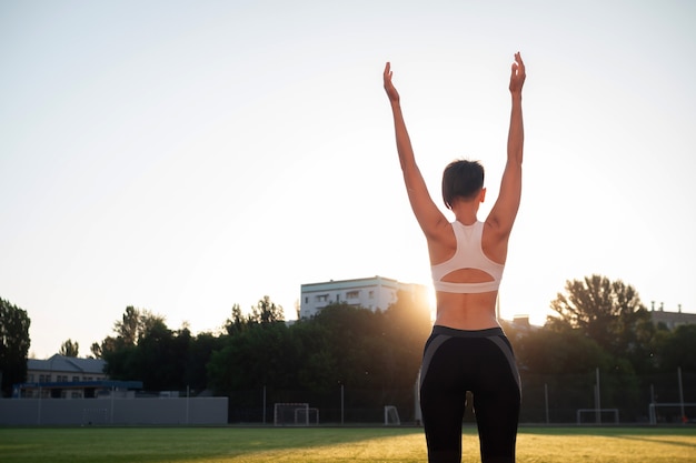 Sport and wellness. Fitness girl in white sneakers doing stretching workout. Fashion sporty woman with strong muscular body training. Fit female stretching at outdoor stadium