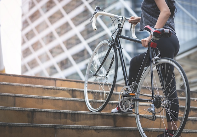 Sport woman is carrying her bike up the stair