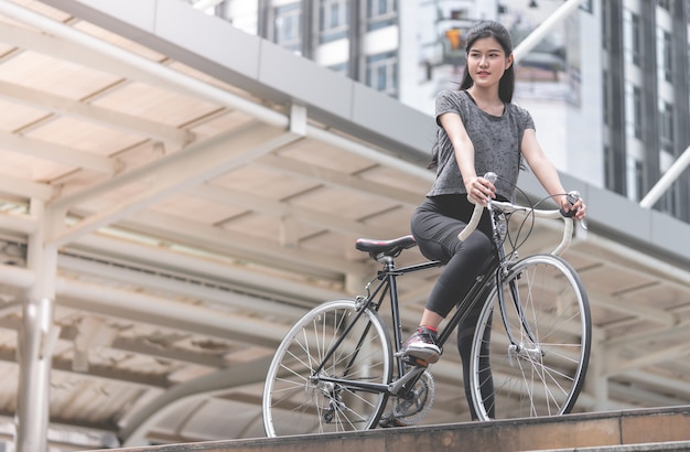 Sport woman is posting with her bike on the stair