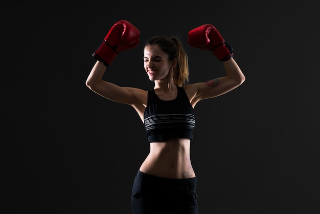 Sport woman with boxing gloves on dark background