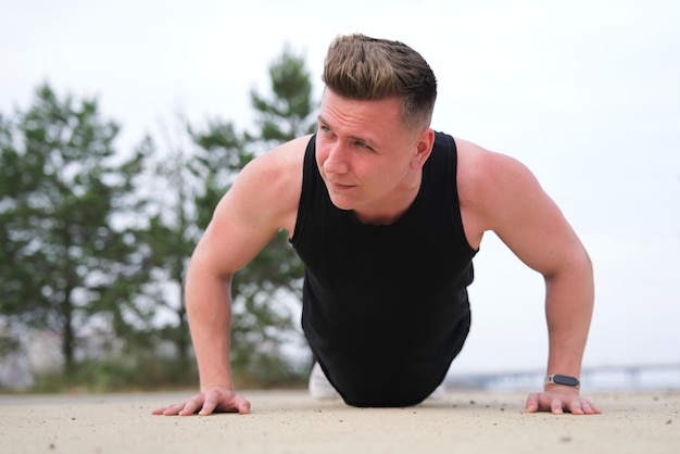 Sportive fit fitness man athlete athletic guy doing push ups workout exercise  training outdoor