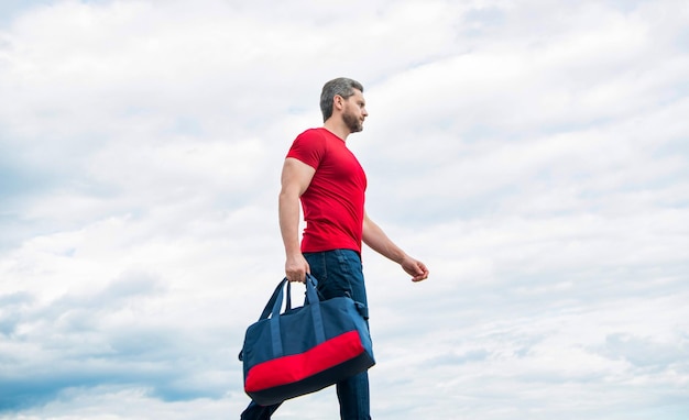 Sportive man traveling with sporty bag sky background sport