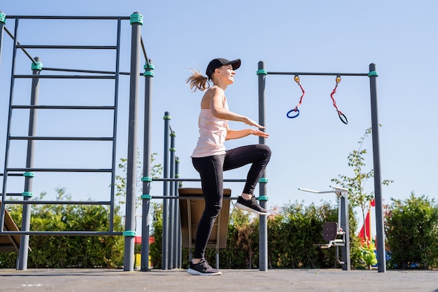 Sportive woman working out on the sports ground in sunny summer day