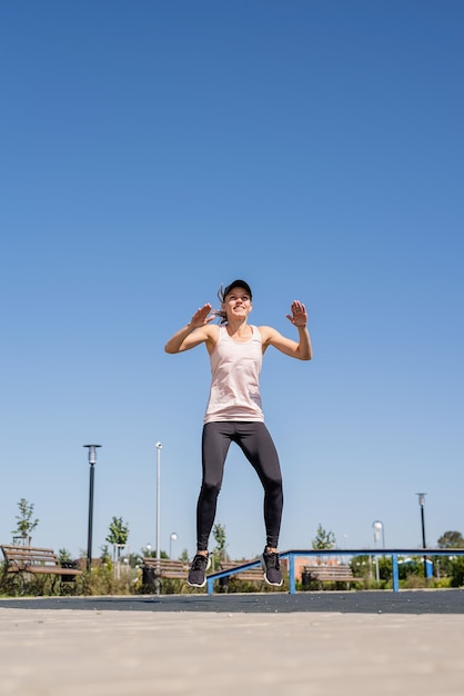 Sportive woman working out on the sports ground in sunny summer day