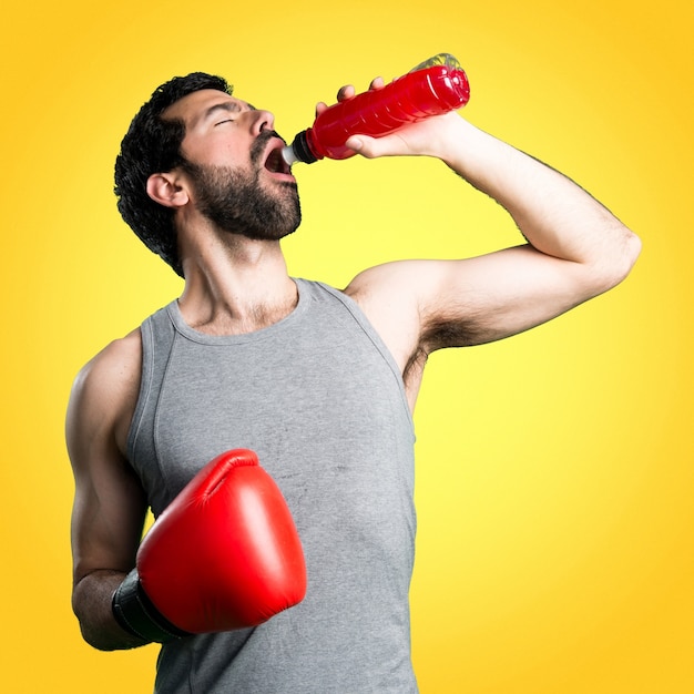 Photo sportman with boxing gloves drinking water soda on colorful background