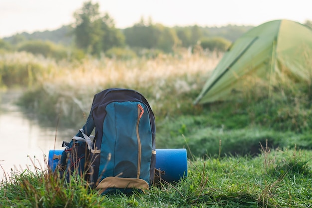 Sports backpack with a rug about a tourist tent on the background of nature and forest.