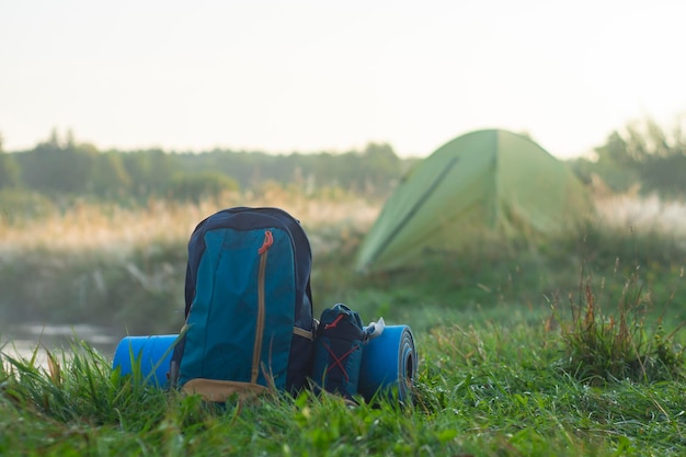 Sports backpack with a rug near a tourist tent on the background of nature and forest