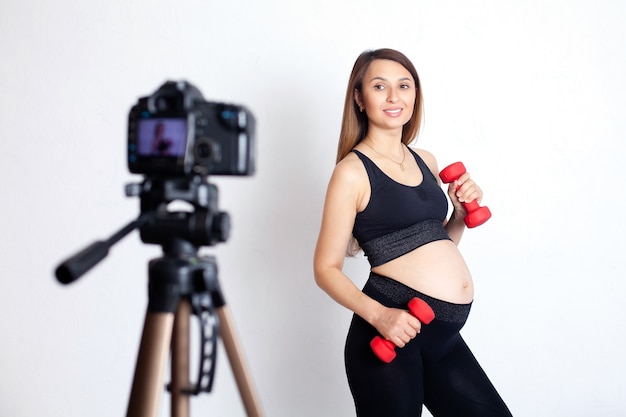 Sports blogger A beautiful pregnant woman plays sports and shoots a workout on camera