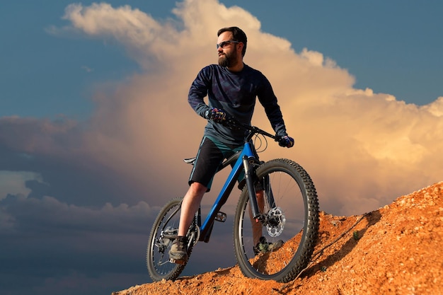 Sports brutal bearded guy on a modern mountain bike Cyclist on the green hills in the spring