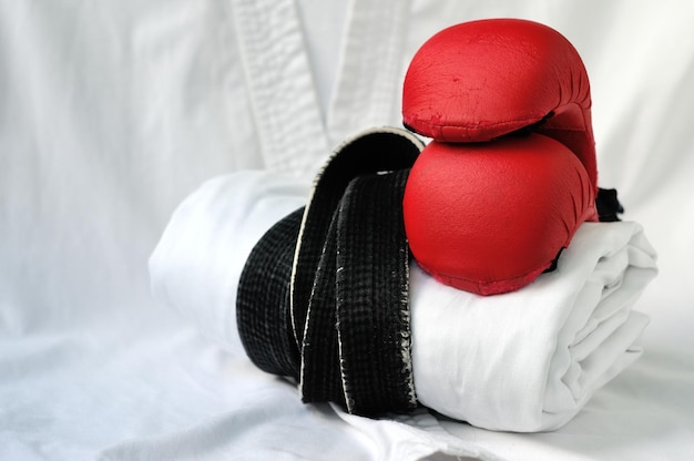 Photo sports equipment for martial arts white kimano with a black belt and red boxing gloves