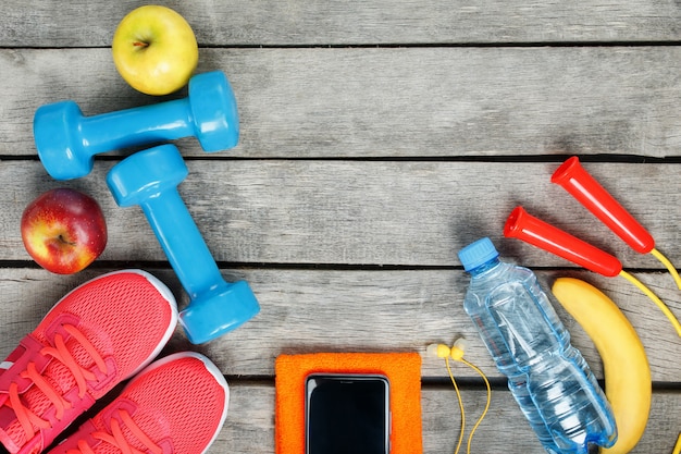 Sports equipment and the smartphone with earphones on a wooden 