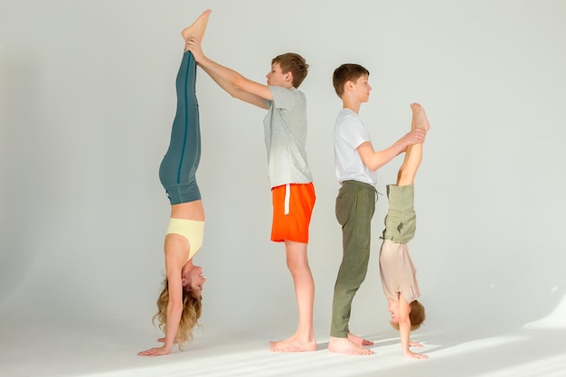 A sports family a slender woman a boy and two teenagers stand on their hands