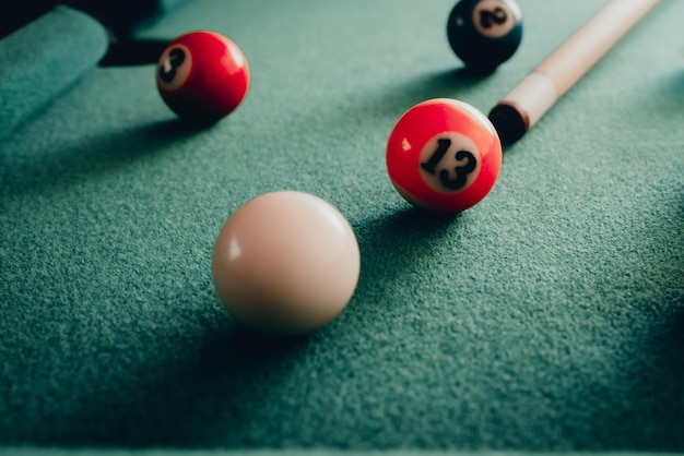 Photo sports game of billiards on a green clothmulti colored billiard balls in the form of a triangle with numbersa cue ball and a triangle on a pool table billiard balls closeuptoned