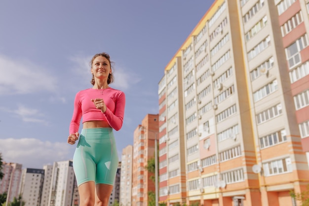 Sports girl in bright sportswear runs in the city