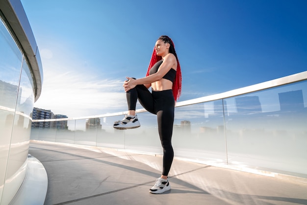 Sports girl, girl in sportswear, outdoor workout, Woman in sports tops, Black clothing for sports, girl with dreadlocks, girl stretches her legs, girl warming up