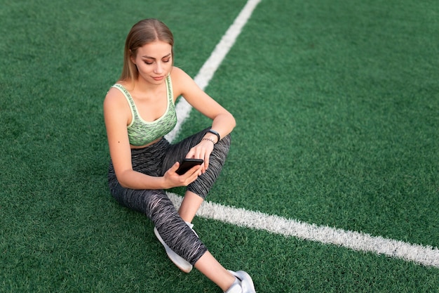 Sports girl sitting and using the phone