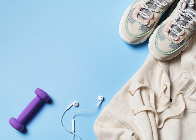 Sports, healthy and fashion concept on blue with sneakers, hoodie and earphones