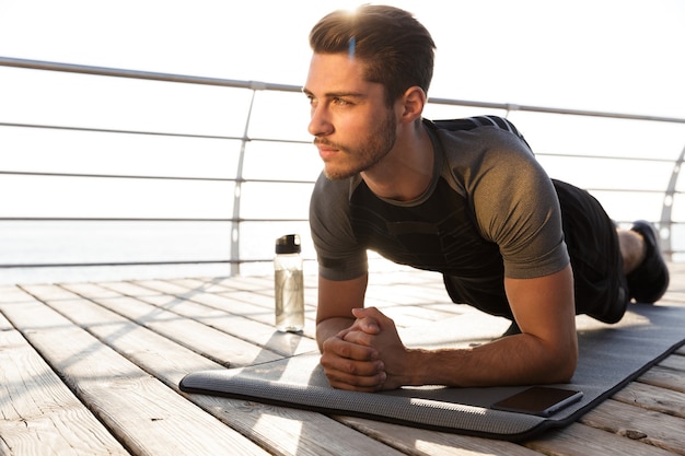 Sports man outdoors on the beach makes sport exercises