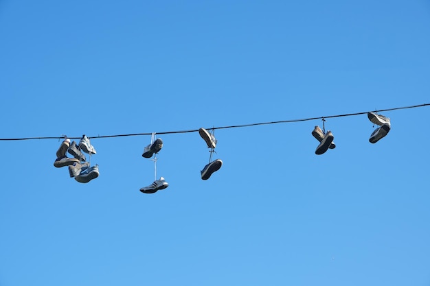 Sports shoes are hanging on wires.Sneakers suspended by laces on electrical wires.