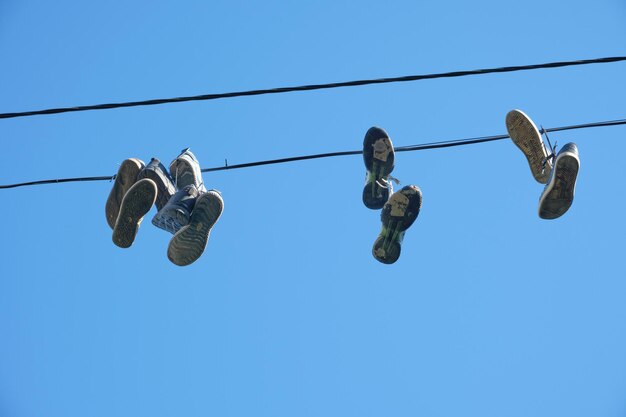 Sports shoes are hanging on wires.Sneakers suspended by laces on electrical wires.