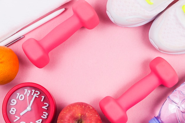 Sports shoes, dumbbell fitness, in the pink background. Different sports tools