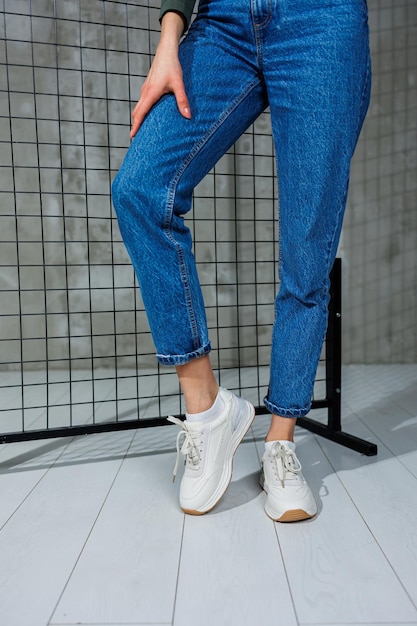 Sports shoes for women Slender female legs in jeans and white stylish casual sneakers Women's comfortable summer shoes Casual women's fashion