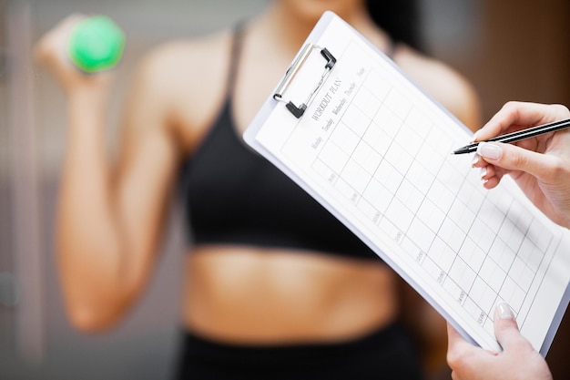 Photo sports trainer amounts to workout plan closeup