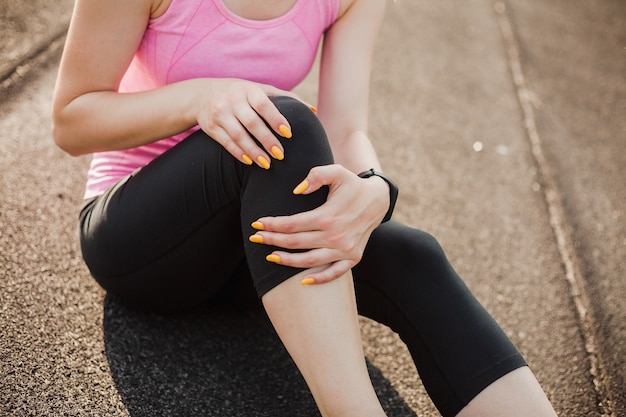 Sports woman clinging to her knee due to injury