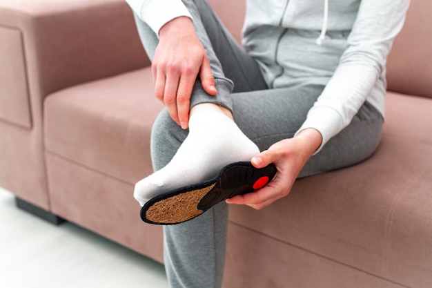 Sports woman fitting orthopedic insoles at home. Treatment and prevention of flatfeet and foot diseases. Foot care, feet comfort. Health care, wearing comfortable shoes