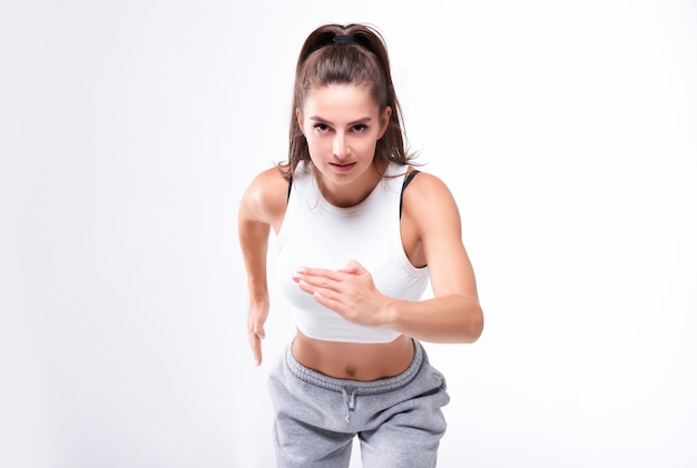 Sports woman runner on a white background Photo of an attractive woman in fashionable sportswear Dynamic movement Side view Sports and healthy lifestyle