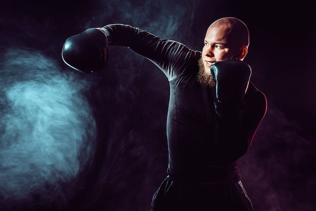 Sportsman boxer fighting, hitting side impact on black space with smoke