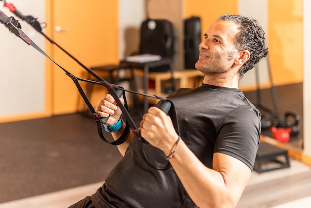 Sportsman doing exercise with trx fitness straps at gym. Concept of trx training.