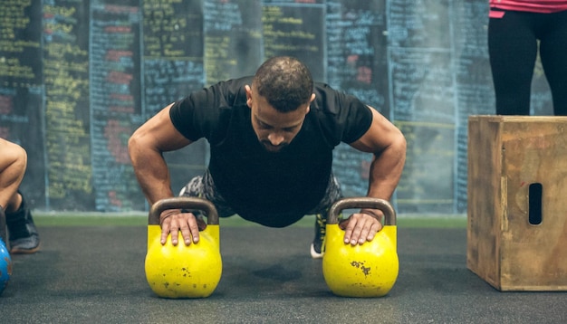 Photo sportsman doing pushups with kettlebells