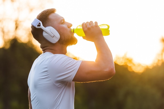 Sportsman drinking energy water from a bottle while resting after a run or workout Healthy lifestyle