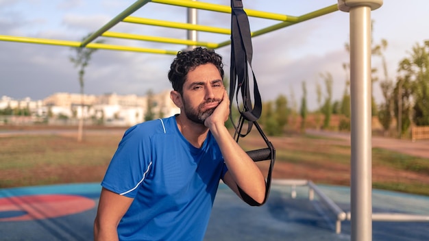 Sportsman not feeling motivated with a TRX workout fitness for exercises outdoor