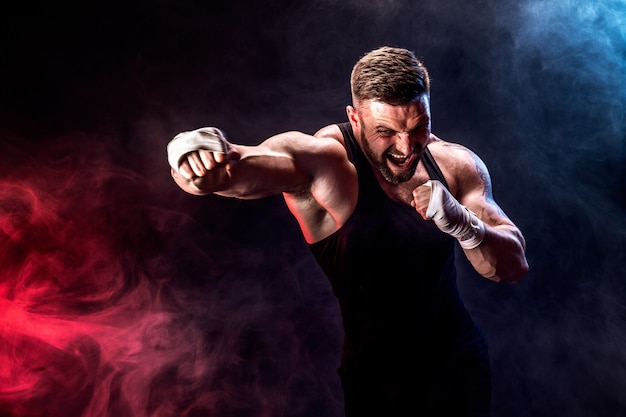 Sportsman muay thai boxer fighting on black wall with smoke.