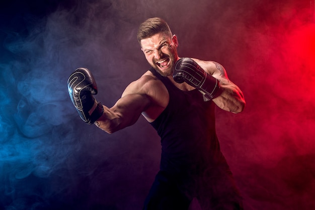 Sportsman muay thai boxer fighting on black wall with smoke.