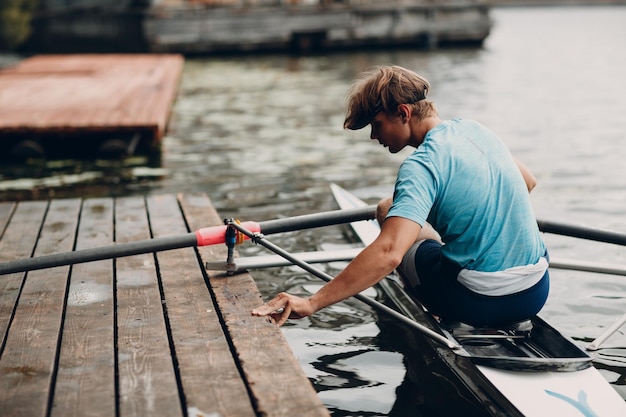 Sportsman single scull man rower prepare to competition with boat