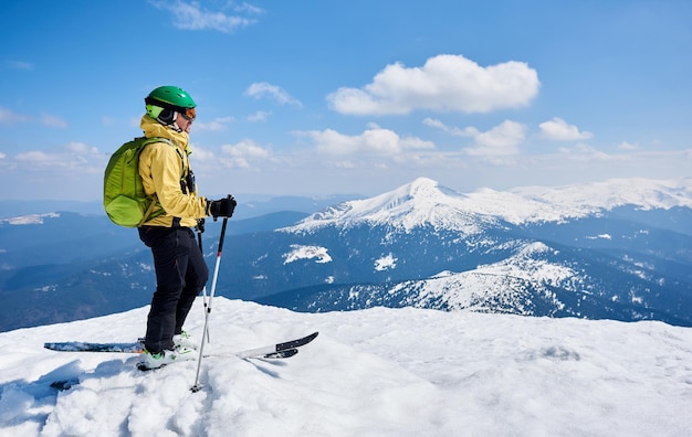 Sportsman skier on skis on background of blue sky and highland landscape Winter skiing concept