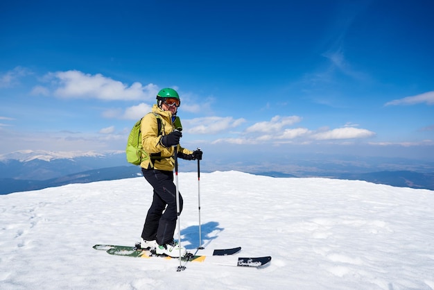 Sportsman skier on skis on snowy valley on background of bright blue sky and highland landscape