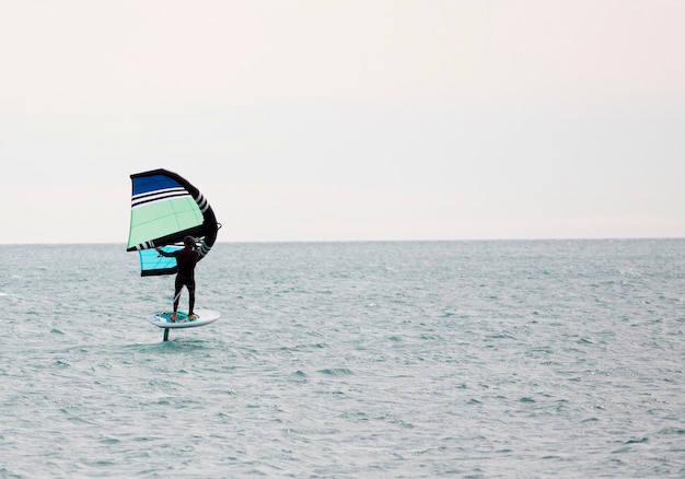 Sportsman with wingfoil sailing in the sea