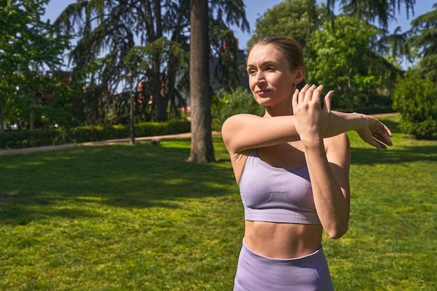 In sportswear a woman stretches her commitment to fitness echoed in the park